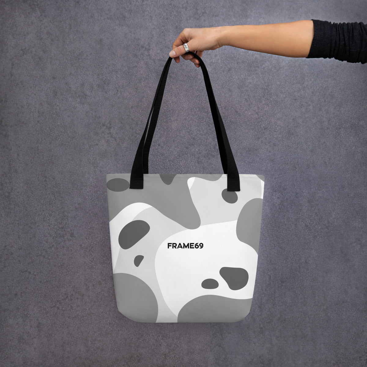 Graphic tote bag with black handles and abstract cow print on white, FRAME69.