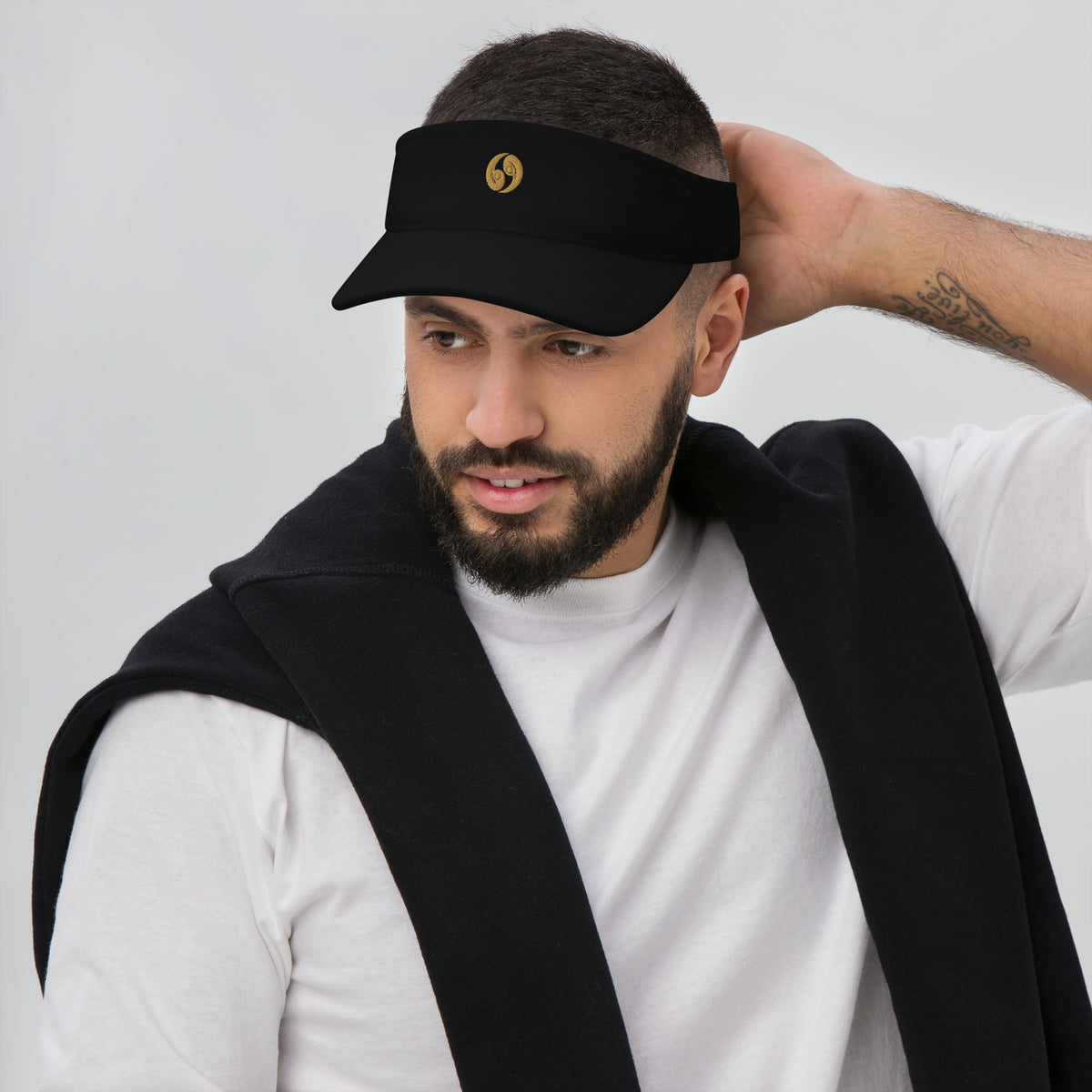 Black classic visor on model with curved brim and small gold emblem at center front